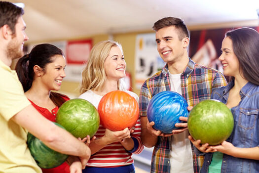 people, leisure, sport, friendship and entertainment concept - happy friends holding balls and talking in bowling club